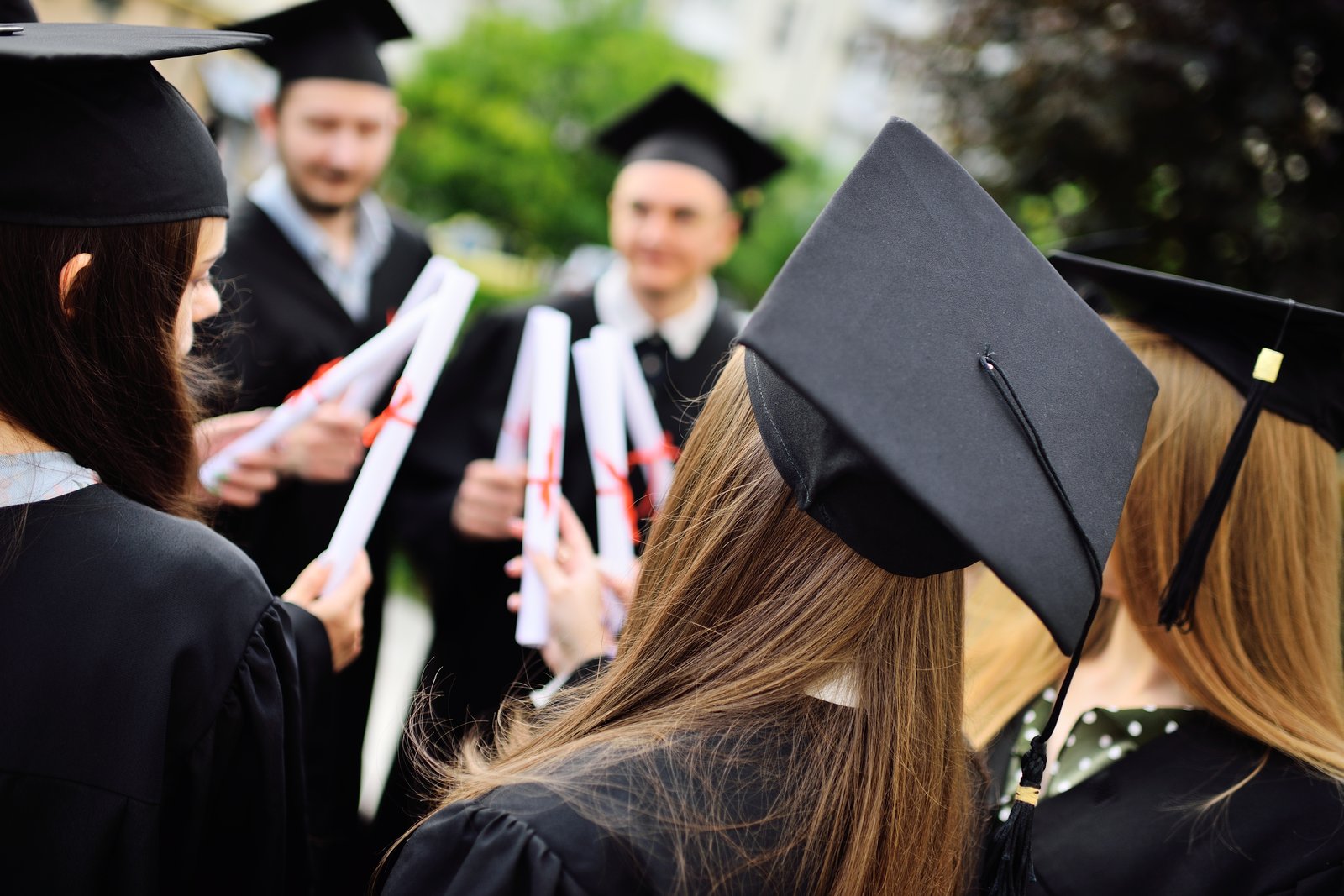 group of university graduates in student robes or mantle and square hats at the graduation ceremony